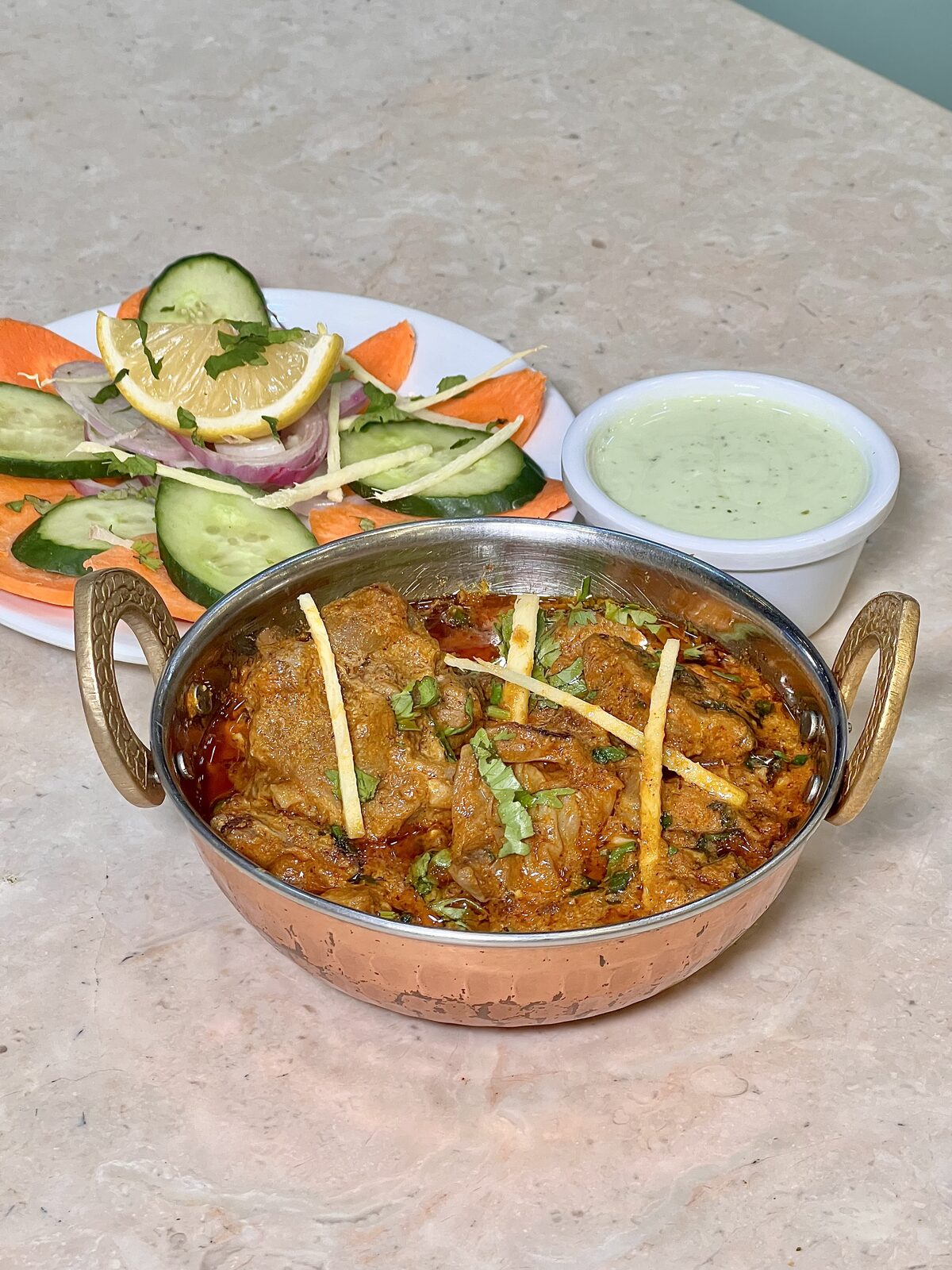 Beef Qorma in a copper karahi with fresh salad